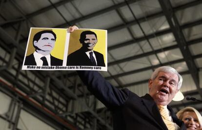 Newt Gingrich muestra una pancarta que equipara las reformas sanitarias de Romney y Obama durante un mítin en Florida.