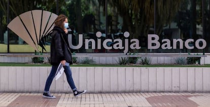 Una mujer pasea ante la sede de Unicaja en Málaga.