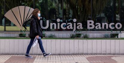 Una mujer pasea ante la sede de Unicaja en Málaga.