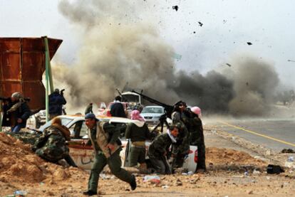 Combatientes rebeldes se protegen de la explosión de un proyectil de tanque en Ras Lanuf.