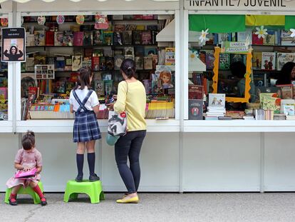 Una madre visita con sus hijas la Feria del Libro en Madrid.