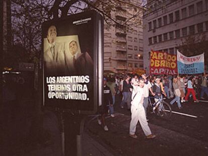 Una manifestación obrera en Buenos Aires pasa ante un cartel electoral de Menem.