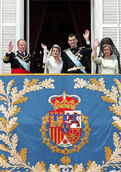 Los recién casados saludan desde el balcón del Palacio Real junto a los Reyes.
