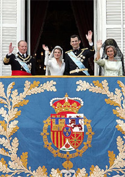 Los recién casados saludan desde el balcón del Palacio Real junto a los Reyes.