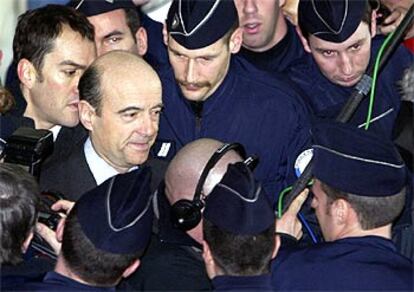 Alain Juppé, rodeado de policías, llega al tribunal de Nanterre que ayer le condenó por corrupción.