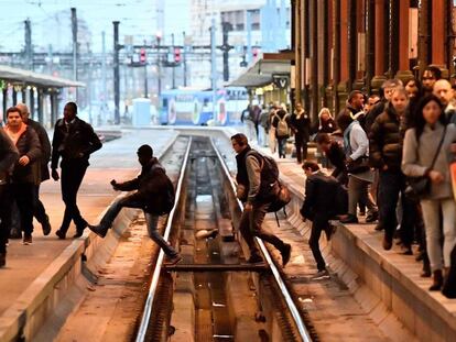 Passageiros cruzam as vias do trem em uma estação de Paris (França).