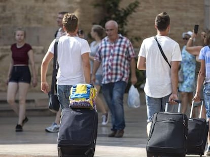 Cuatro j&oacute;venes turistas caminan con su maletas en Valencia. 