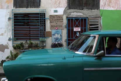 Un coche circula por el centro de La Habana frente a un retrato de homenaje a Castro.