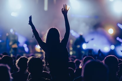 Una joven en una multitud durante un concierto en un festival de música al aire libre.