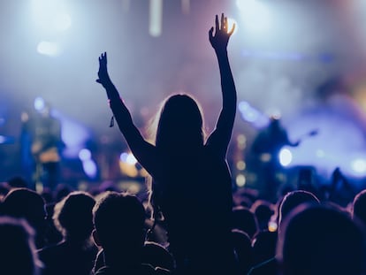 Una joven en una multitud durante un concierto en un festival de música al aire libre.