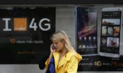 Una usuaria habla por móvil junto a una publicidad de Orange.