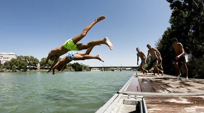 Unos chicos se lanzan al r&iacute;o Guadalquivir en el Paseo de la O, en Triana.