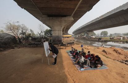 Un maestro indio llamado Kuldeep Maurya enseña a los estudiantes en una escuela improvisada bajo el puente de una línea de metro en Nueva Delhi, en la India.