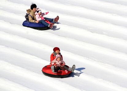 Varias personas en una atracción cubierta de nieve durante el carnaval de hielo en el parque de Taoranting, en Pekín (China).