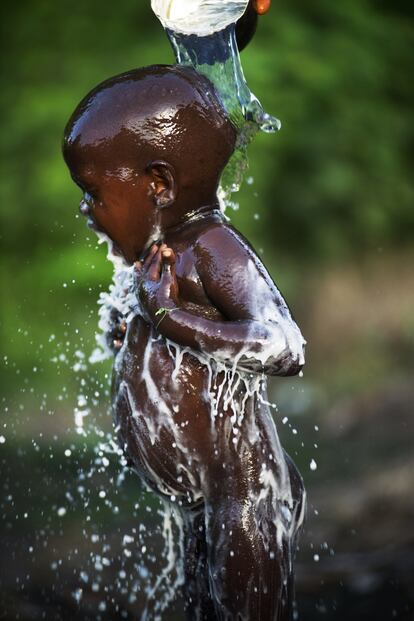 Un niño se asea en un pequeño pozo de agua construido por la comunidad de una pequeña aldea del interior en la región de Gabú, cerca de la frontera entre Guinea Conakry y Guinea Bisáu en el año 2019. En esta zona, la falta de agua potable en los hogares es total por lo que este recurso es más valioso que el oro, tal como ellos dicen. De él dependen para cocinar, asearse… Y conseguirla les supone caminar a veces hasta más de 20 kilómetros diariamente.