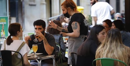 Una camarera atiende a unos clientes en una terraza.