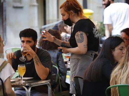 Una camarera atiende a unos clientes en una terraza.