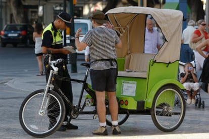 Un agente de Málaga revisa la documentación del conductor de una <i>bicitaxi</i> el pasado verano.