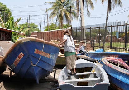 Un pescador revisa un barco que fue sacado del agua antes de la llegada del huracán 'Beryl', en Port Royal, Jamaica.