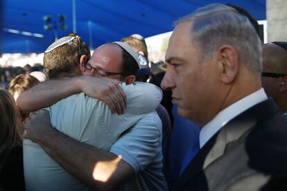 El primer ministro israelí, Benjamin Netanyahu (d) junto a Avi Fraenkel (i) y Ofir Yifrah (2-i), padres de Gil-Ad Shaer y Naftali Fraenkel, que tenía la doble nacionalidad israelí y estadounidense, dos de los tres jóvenes israelíes que fueron secuestrados y asesinados en Cisjordania, en el funeral colectivo que se lleva a cabo en Modi'in (Israel).