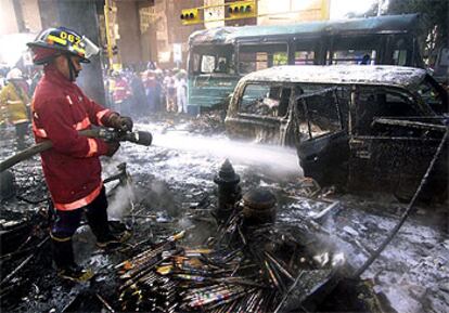 Un bombero apaga el fuego causado por la explosión de una camioneta con fuegos artificiales en Caracas.