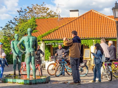 Varios ciclistas observan la escultura de David Cerny, localizada en el Museo Franz Kafka en Praga.