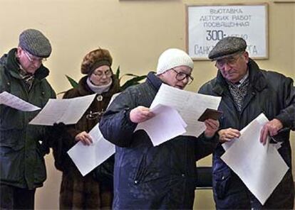 Unos votantes rusos leen en un colegio electoral del centro de Moscú las papeletas antes de depositarlas en las urnas.