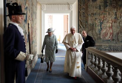 La reina Isabel II y Benedicto XVI, seguidos por el príncipe Felipe, caminan por los pasillos del Palacio de Holyroodhouse, la residencia oficial de la monarca en Escocia.
