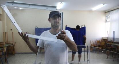 Un operario prepara una urna para el referendum del 5J en un instituto de Atenas.