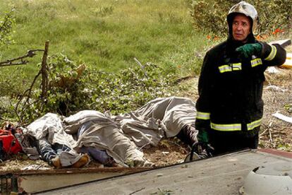 Un bombero trabaja en el lugar del accidente junto a varios de los cadáveres.