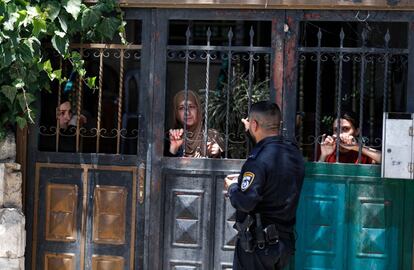 Un policía israelí se detiene frente a la antigua casa de la familia palestina Siyam, mientras algunos de sus miembros miran desde una puerta, durante su desalojo en el vecindario palestino de Silwan (Jerusalén). Una familia palestina fue desalojada después de que los colonos israelíes ganaran una batalla judicial que duró más de dos décadas. El apartamento en disputa en el barrio palestino de Silwan fue el hogar de una mujer de 53 años y sus cuatro hijos, según la ONG israelí Peace Now.