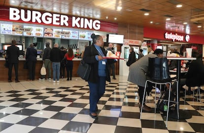 Varios asistentes a la cumbre del clima consumen comida rápida de Burger King en envases de plástico.