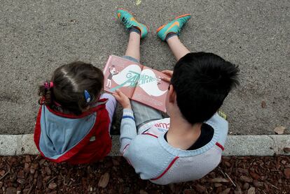 Unos niños leen un cuento infantil en la Feria del Libro de Madrid.