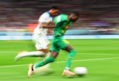 Jude Bellingham, de Inglaterra, y Pape Sarr, de Senegal, corren por la banda. 
