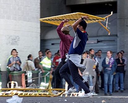 Dos jóvenes violentos arremeten contra la policía con una valla metálica cerca del estadio Bernabéu.