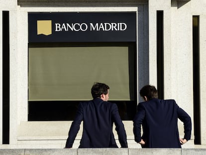 Dos personas conversan frente a una oficina del Banco Madrid, en 2015 en la capital.