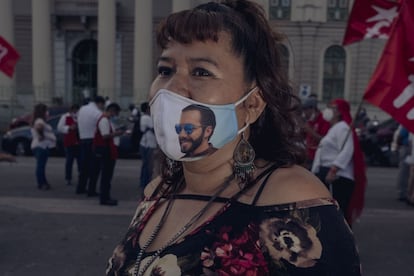 Yanira Martínez, de 44 años, muestra orgullosa un cubre bocas con el retrato de Bukele en una calle de San Salvador. 