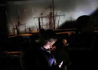 Un cadete mira su teléfono delante de la nave de guerra de Enrique VIII, el Mary Rose, después de la renovación del museo en Portsmouth, Inglaterra. El buque, que fue levantado de entre el Solent en 1982, se puso en marcha en Portsmouth en 1511 y se hundió en 1545 en la batalla del Solent.