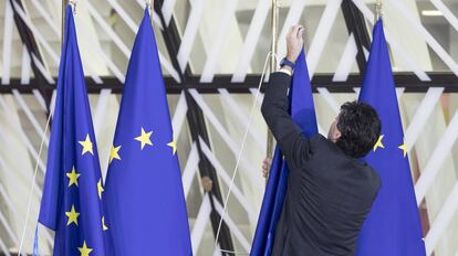 Una persona coloca banderas de Europa en la sede del Consejo Europeo.