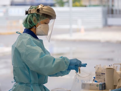 Personal sanitario toma muestras a usuarios, en su propio vehículo, para el test PCR y análisis de coronavirus en el hospital militar de Sevilla.