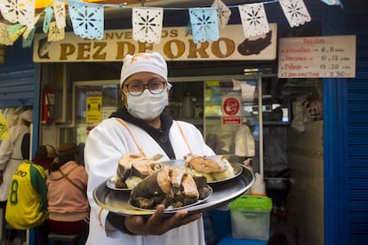 Una empleada del restaurante El Pez de Oro muestra un plato de thimpu de trucha y carachi. La primera, especie introducida en el lago Titicaca, se mezcla no solo en sus aguas sino también en la gastronomía con la nativa.