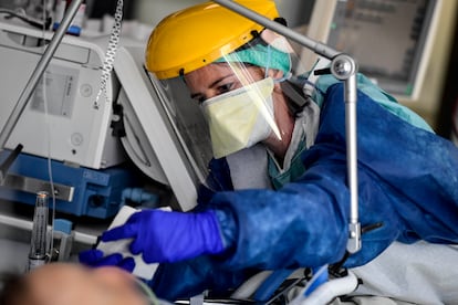 Equipe médica vestida com equipamento de proteção individual (EPI) cuida de um paciente na unidade de terapia intensiva na Bélgica.