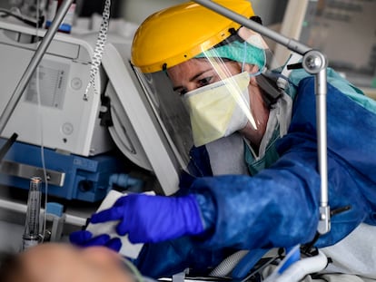 Equipe médica vestida com equipamento de proteção individual (EPI) cuida de um paciente na unidade de terapia intensiva na Bélgica.