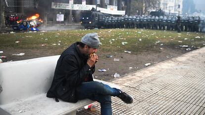 Un hombre come al margen de enfrentamientos que se llevan a cabo frente al Congreso, en Argentina, en 2024.