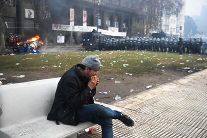 Un hombre come al margen de enfrentamientos que se llevan a cabo frente al Congreso, en Argentina, en 2024.
