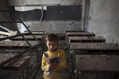 Ali, de 9 años, posa en su antigua clase de la escuela Istiqlal destruida por un bombardeo de la aviación en el barrio de Maadi en Alepo.