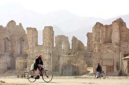 Dos afganos pasan frente a las ruinas de varios edificios en lo que fue el centro administrativo de  Kabul.