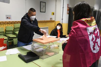 Una joven con una bandera de León atada a su cuello vota en el colegio electoral de Cistierna (León).