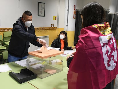 Una joven con una bandera de León atada a su cuello vota en el colegio electoral de Cistierna (León).
