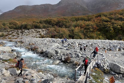 Turistas cruzan un arroyo en camino a la Laguna de los Tres, una de las principales rutas de trekking en El Chaltén.
